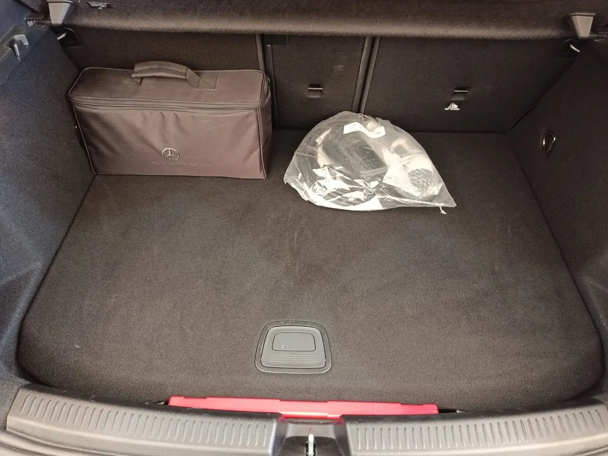 Coffre ouvert de Mercedes Classe A 250 e Business Line noir, vue plongeante avec sac Mercedes et accessoires dans le coffre.