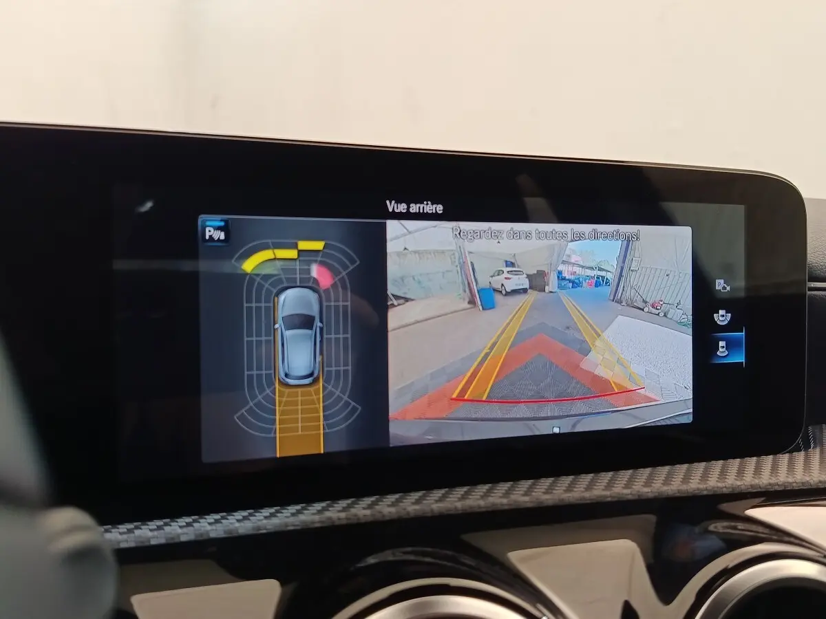 Écran tactile intérieur montrant la caméra de recul et les capteurs de stationnement d'une Mercedes Classe A noire.