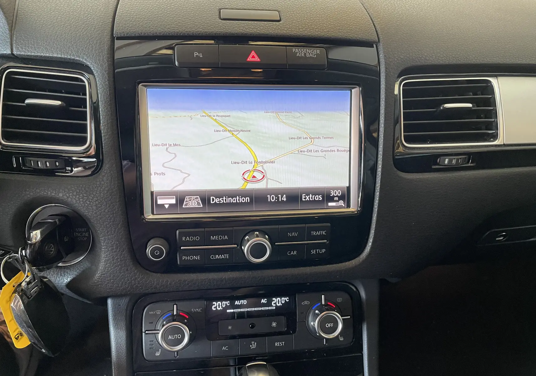 Vue rapprochée du tableau de bord noir du Volkswagen Touareg 2012, avec écran GPS et commandes de climatisation digitales.