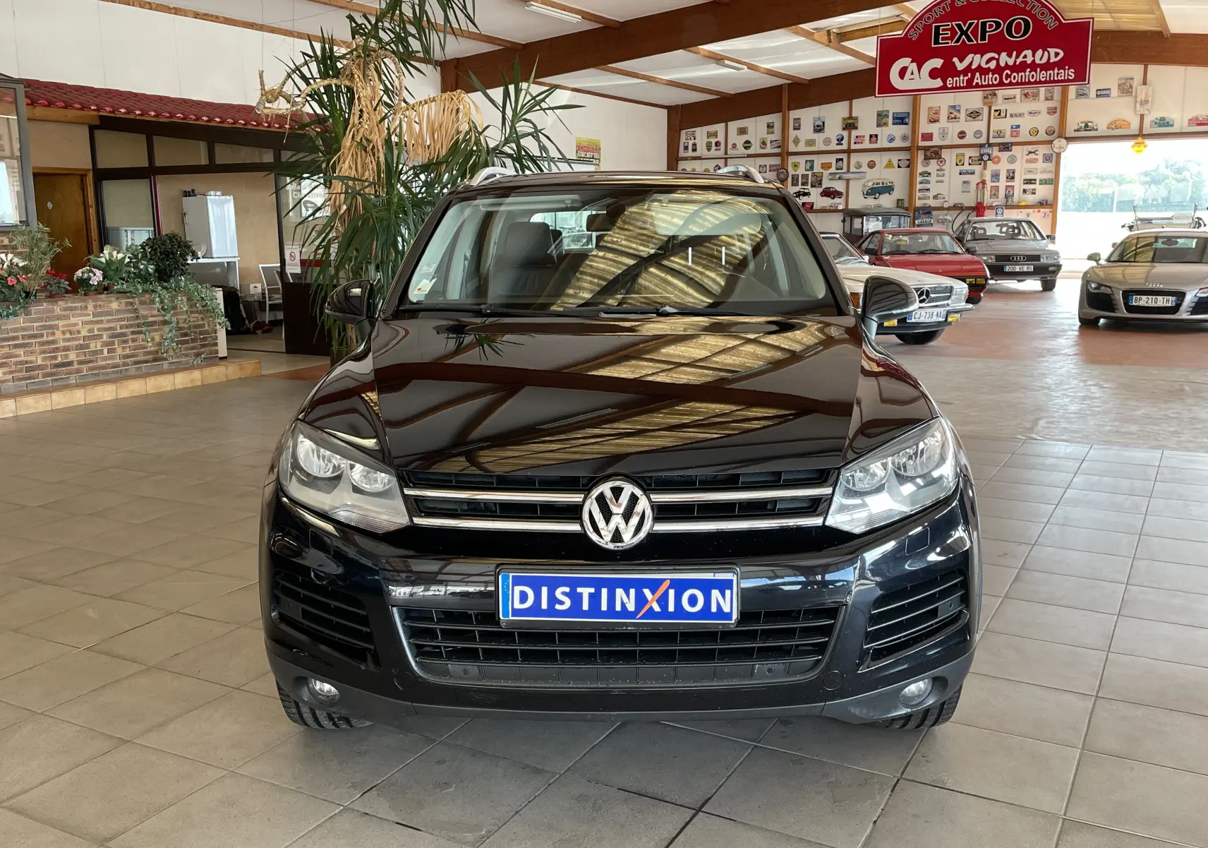 Vue frontale d'un Volkswagen Touareg noir 2012 exposé en intérieur avec plaque Distinxion visible.