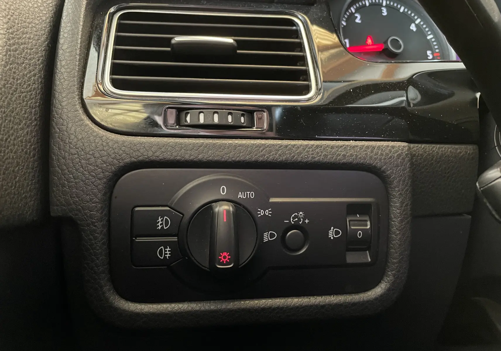 Gros plan sur le panneau de commande des phares du Volkswagen Touareg noir 2012, avec molette allumée sur veilleuses.