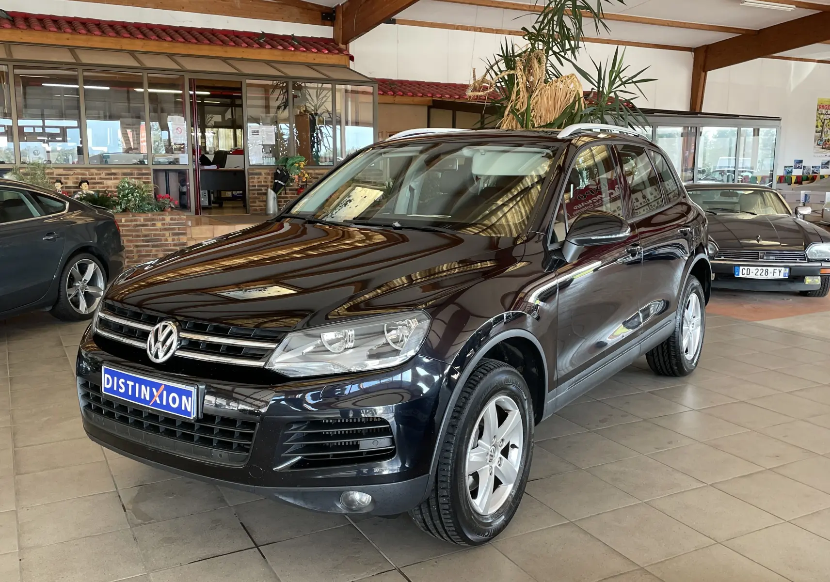 Volkswagen Touareg noir 3/4 avant droit dans un showroom, mettant en valeur ses lignes et jantes argentées.