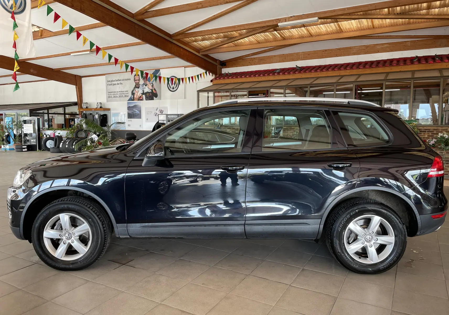 Profil côté gauche d'un Volkswagen Touareg noir 2012, 5 portes, en intérieur avec jantes alliage visibles.