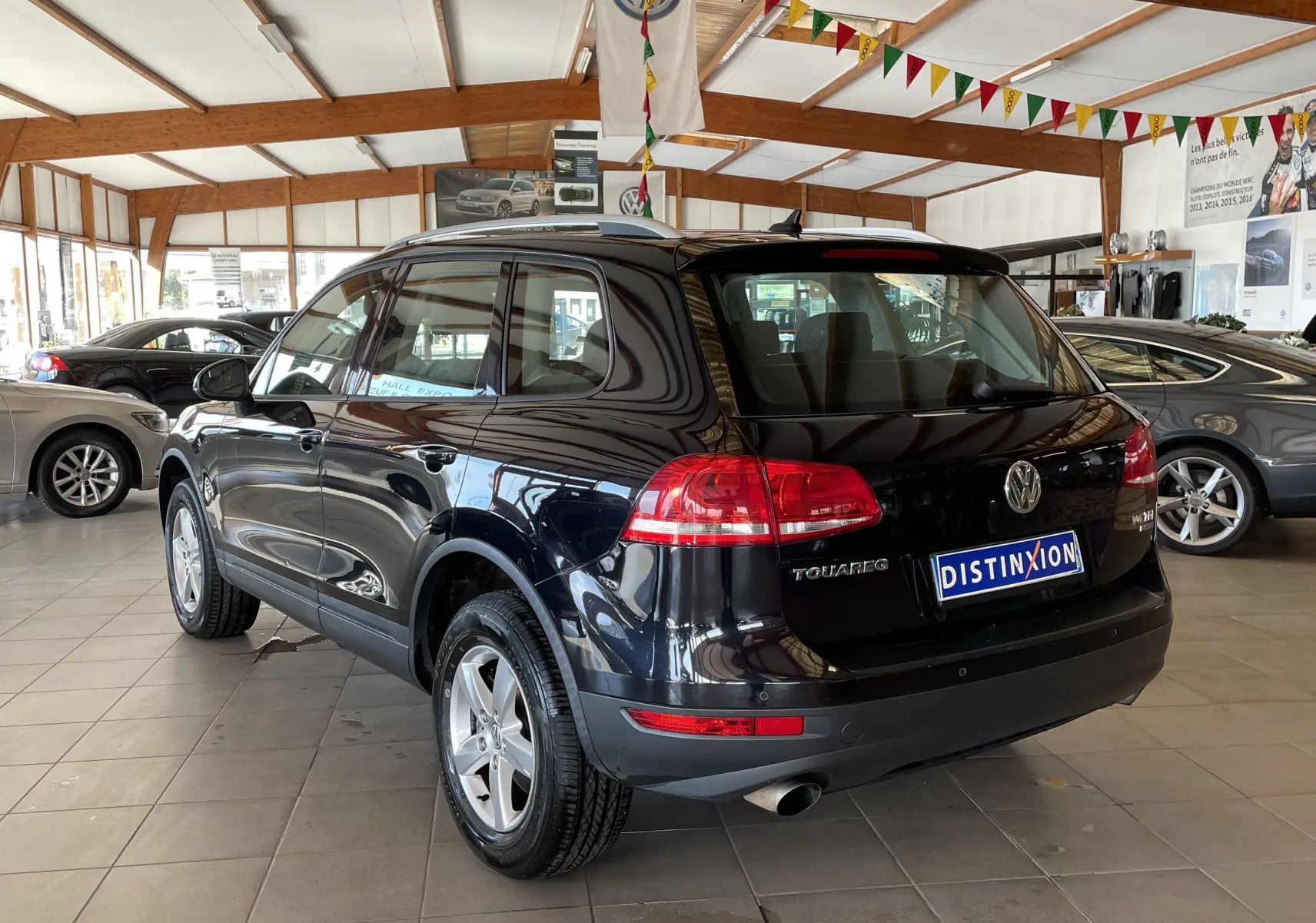 Volkswagen Touareg noir vue 3/4 arrière droit dans un showroom lumineux avec plaques Distinxion.
