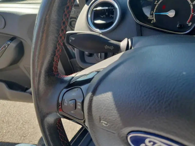 Gros plan sur le volant cuir noir et les commandes multifonctions d'une Ford Fiesta Black Edition 2015, côté conducteur.