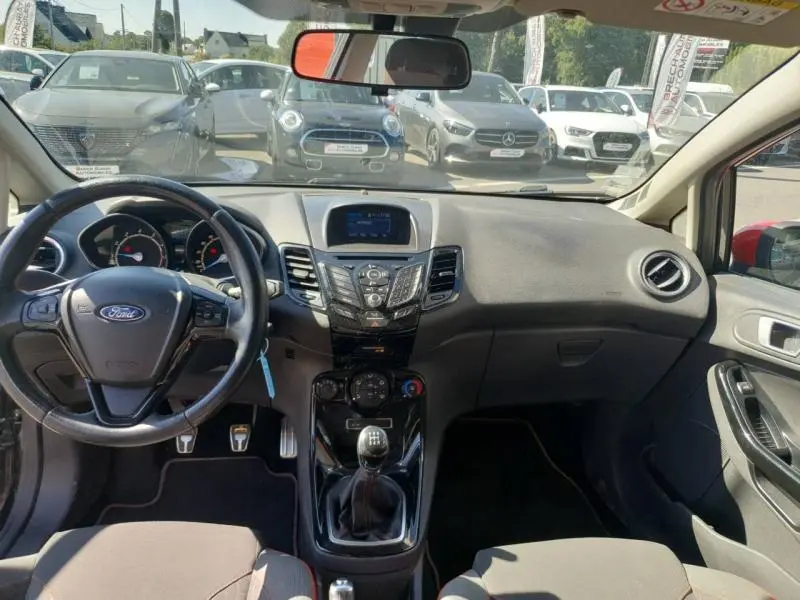 Vue intérieure avant du tableau de bord et volant cuir multifonction d'une Ford Fiesta noire avec boîte manuelle.