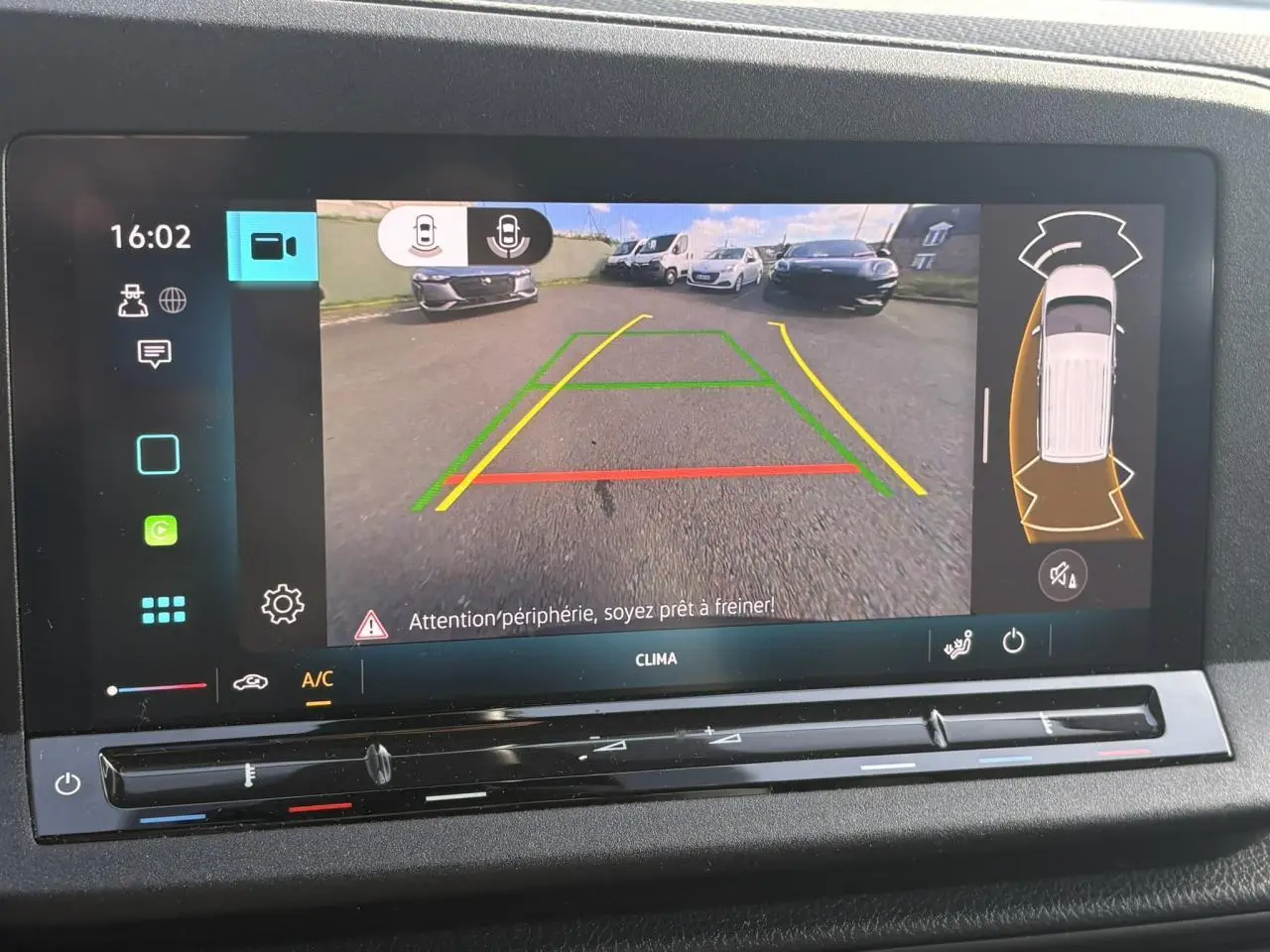 Écran de caméra de recul du Volkswagen Caddy 2024 affichant les lignes de guidage et l'alerte de freinage automatique.