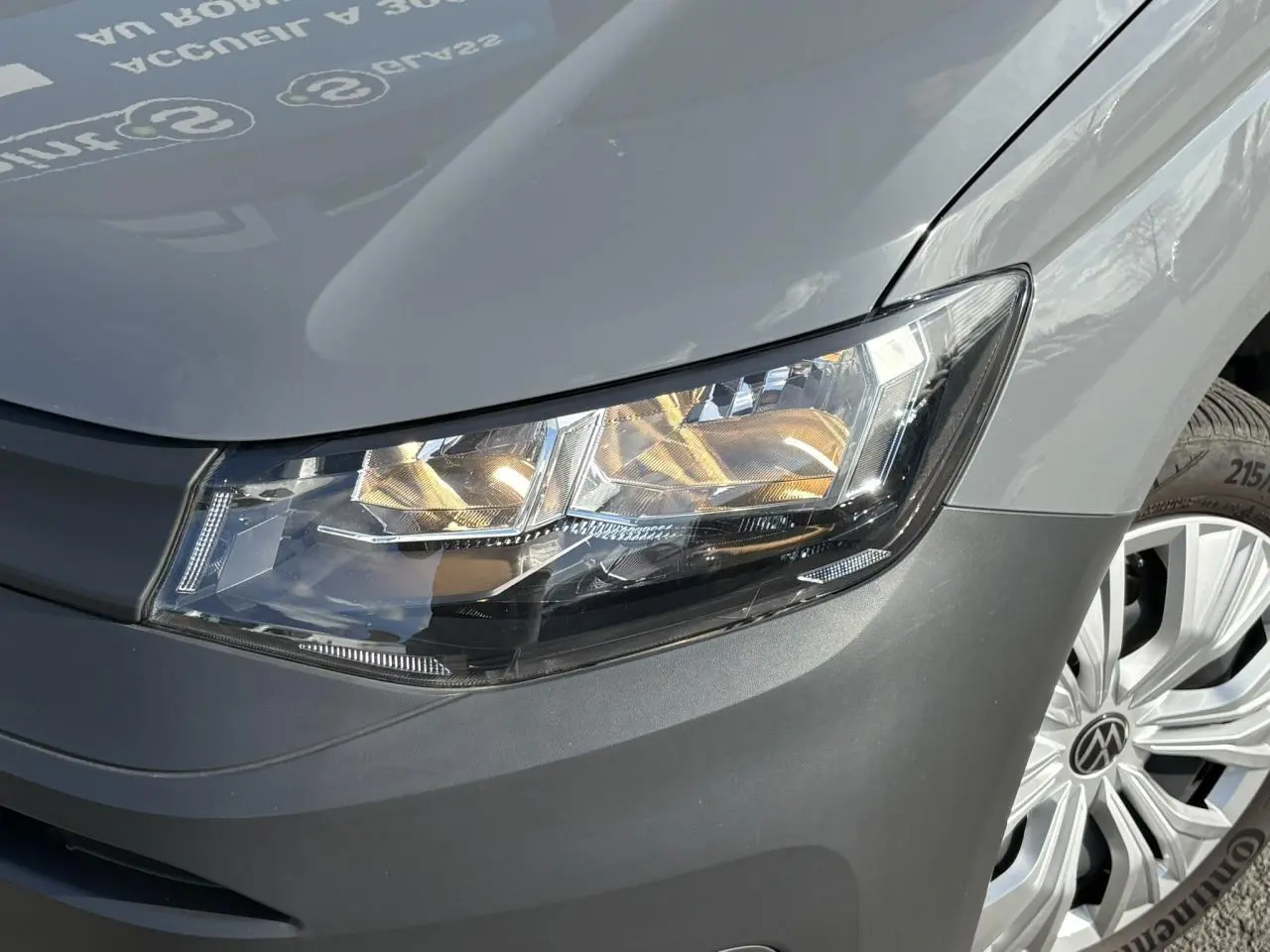 Gros plan sur l'avant droit du Volkswagen Caddy 2024 Pure Grey, mettant en valeur le phare et la jante alu.