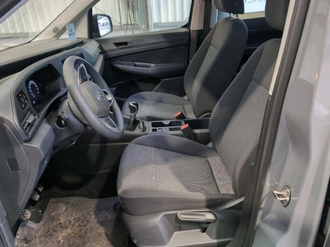 Vue intérieure côté conducteur du Volkswagen Caddy Maxi 2024 en Pure Grey, montrant sièges et tableau de bord.