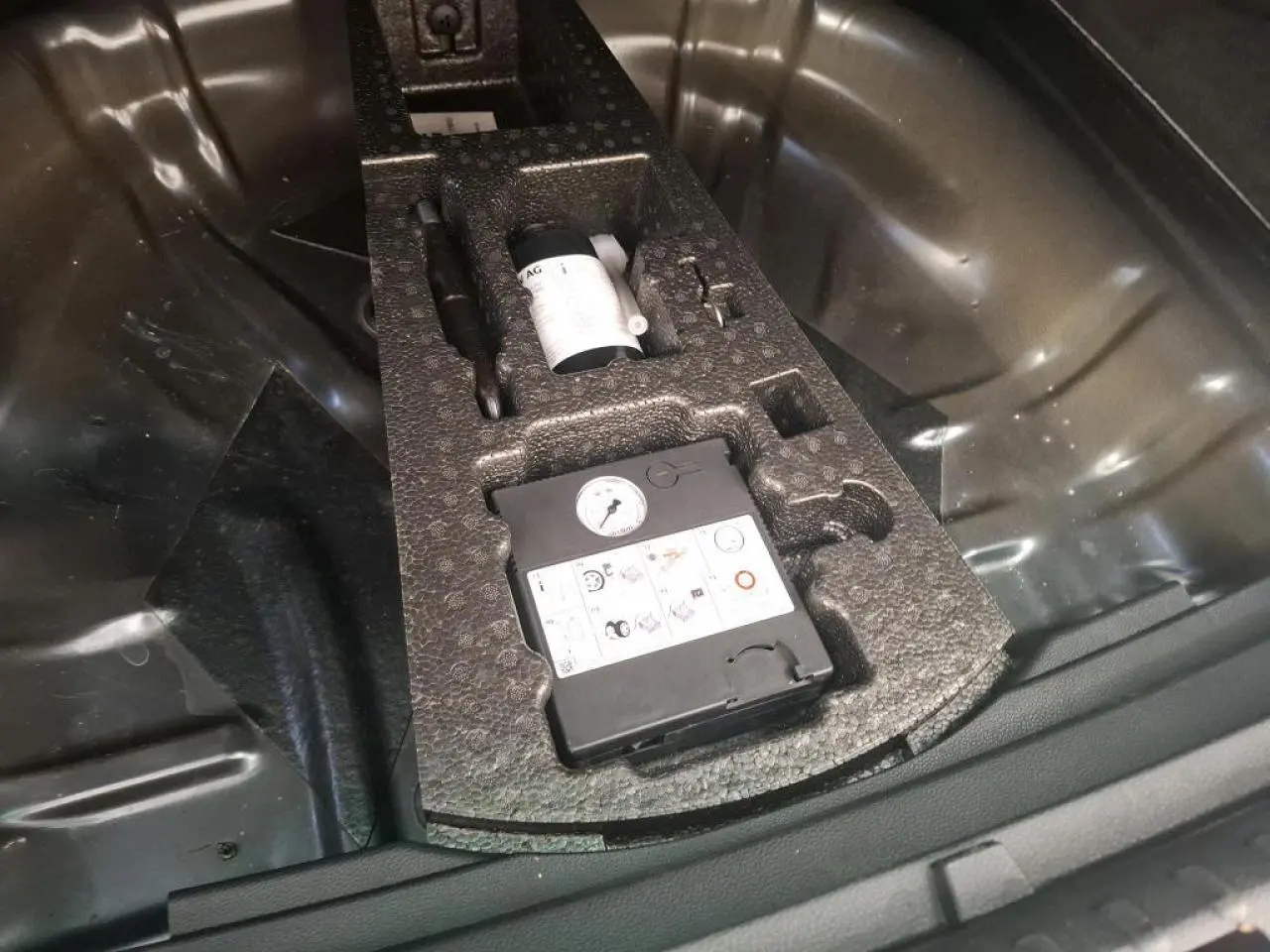 Vue rapprochée du coffre du SEAT Ateca gris clair 2019 montrant le kit anti-crevaison rangé dans la roue de secours.