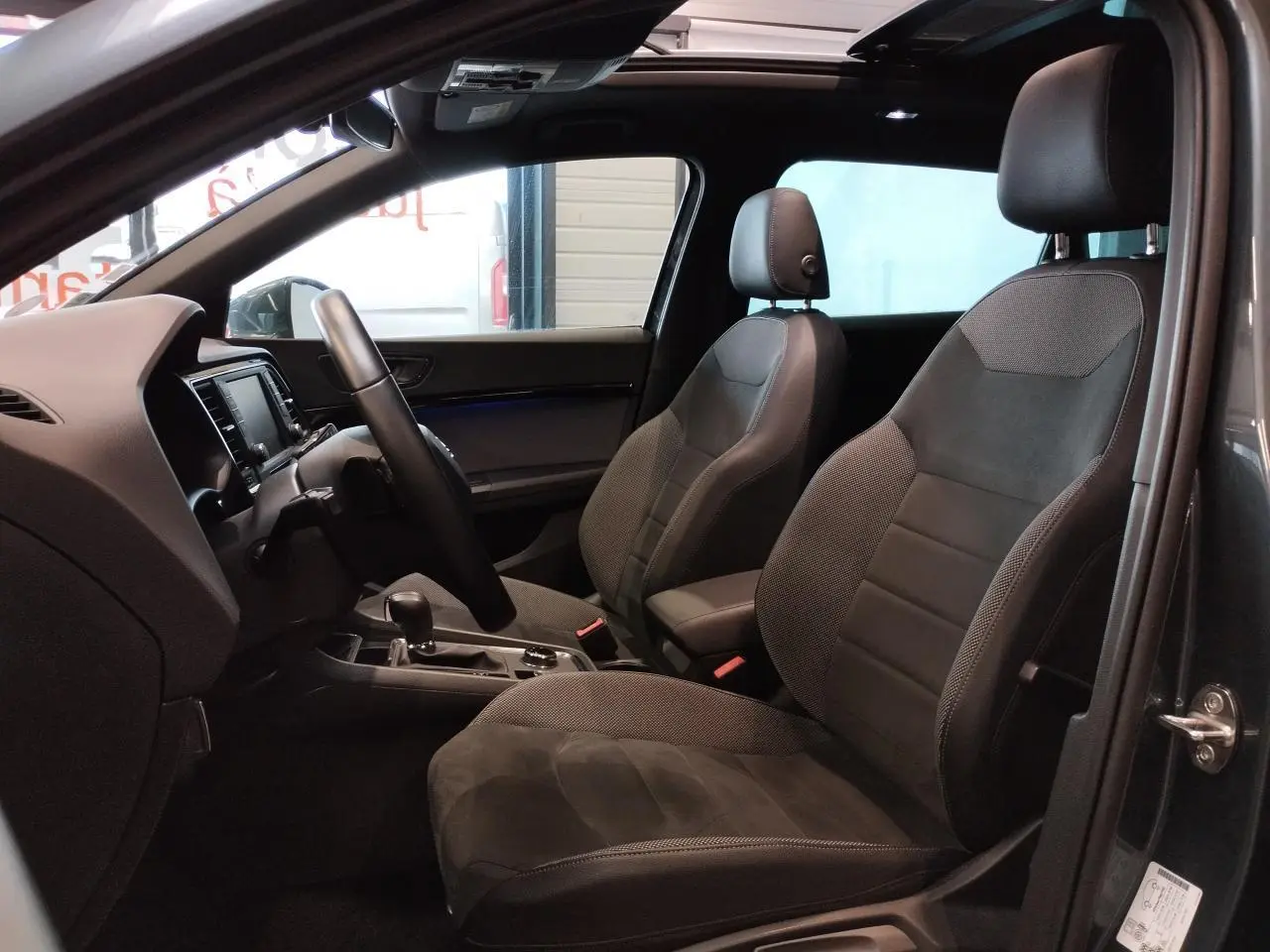 Vue intérieure côté gauche du SEAT Ateca gris clair 2019, mettant en valeur les sièges en alcantara et le toit ouvrant panoramique.