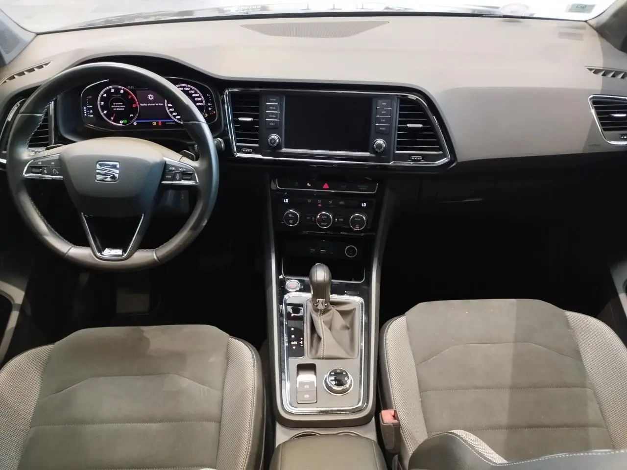 Vue intérieure avant du tableau de bord et console centrale du SEAT Ateca 2019 avec sellerie alcantara brun et volant cuir noir.