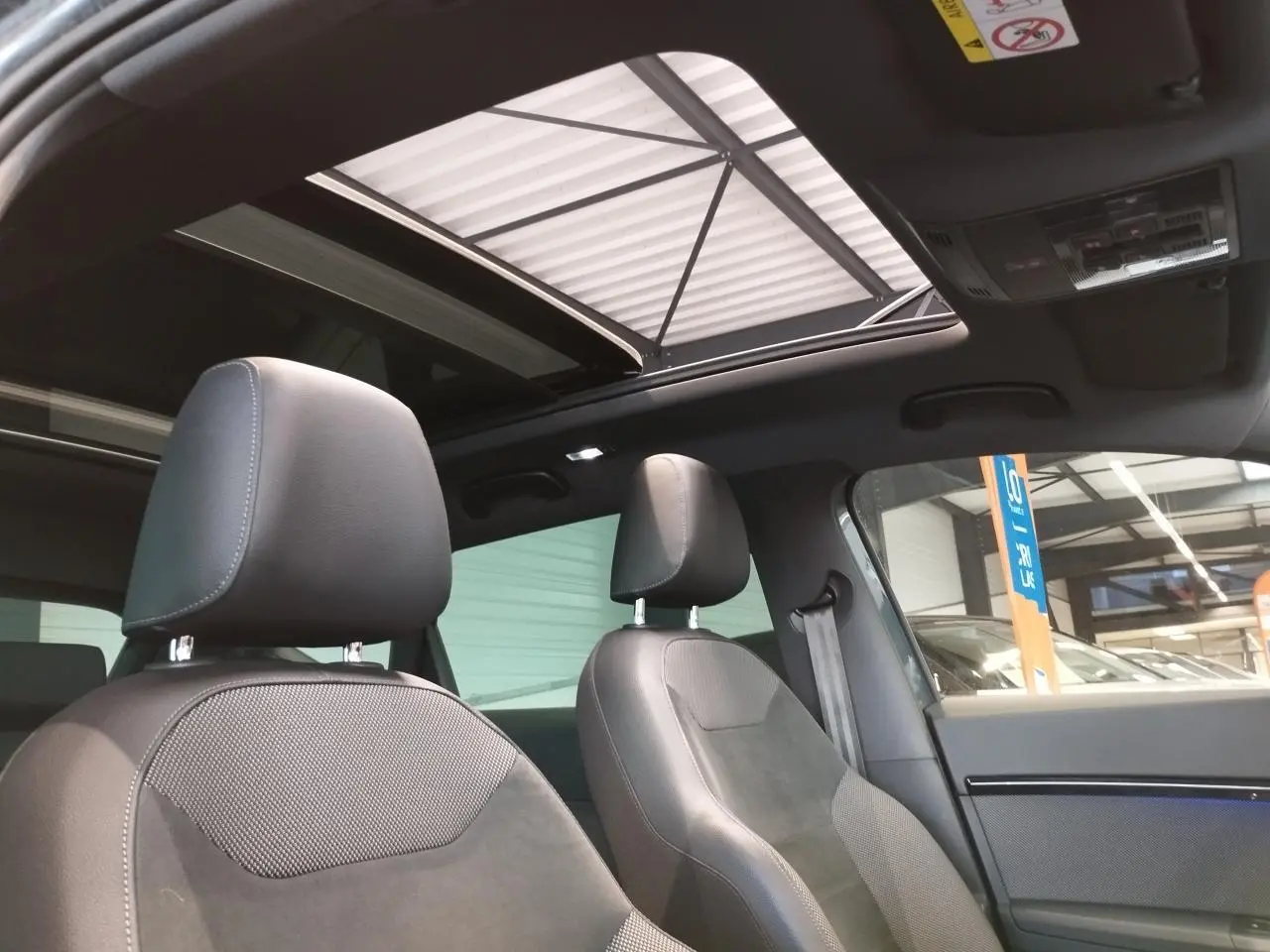 Vue intérieure avant du SEAT Ateca gris clair avec toit ouvrant panoramique et sièges en alcantara brun.