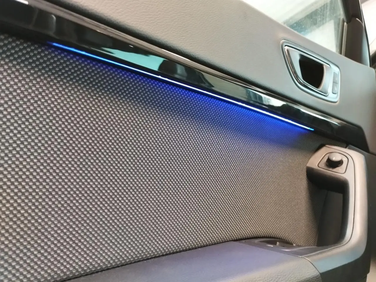 Détail de la porte avant droite du SEAT Ateca gris clair avec éclairage d’ambiance bleu et commande de rétroviseur.