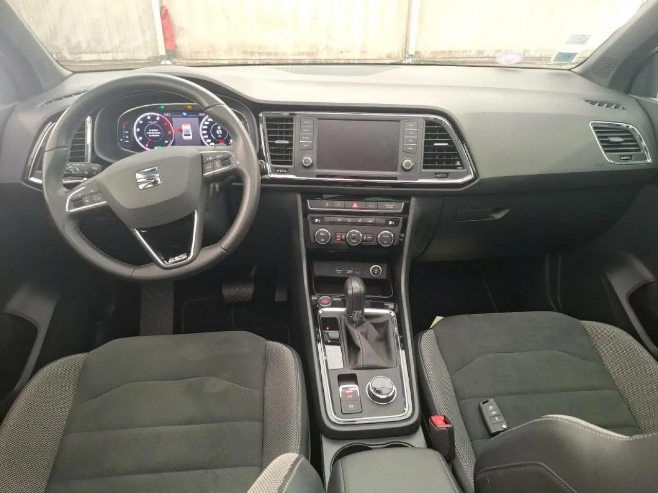 Vue intérieure avant du tableau de bord et console centrale du SEAT Ateca gris clair avec volant multifonctions et écran tactile.