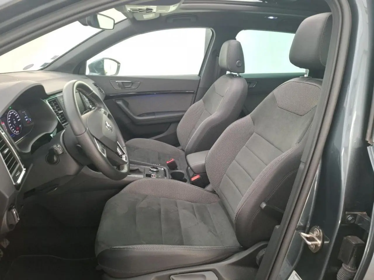 Vue intérieure côté conducteur du SEAT Ateca gris clair, mettant en valeur les sièges en alcantara et le grand toit ouvrant panoramique.