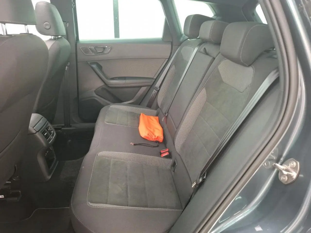 Vue côté droit de la banquette arrière en alcantara brun avec un sac orange posé, intérieur du SEAT Ateca gris clair.