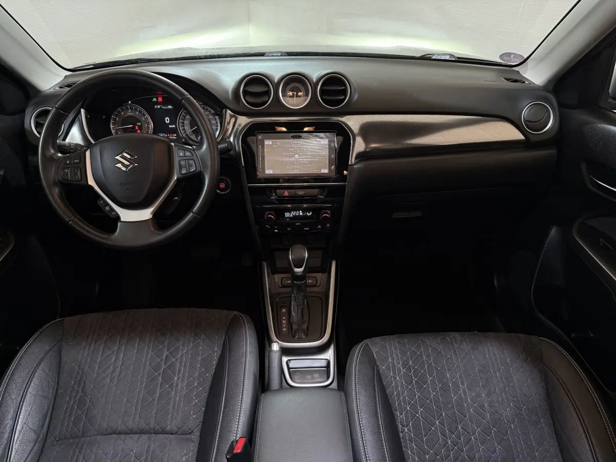 Vue intérieure avant du Suzuki Vitara noir 2022, volant cuir alu multifonctions et écran tactile central.