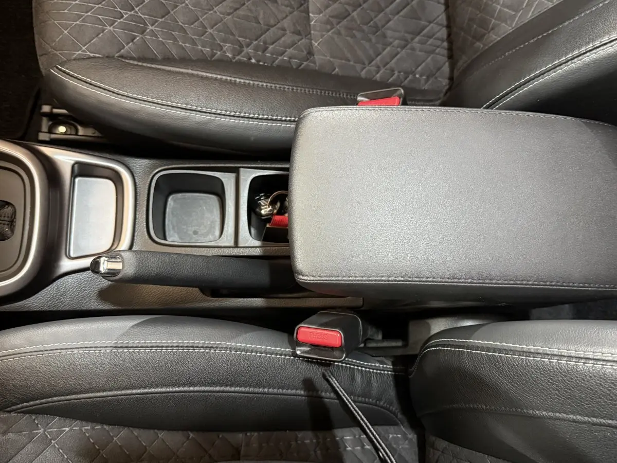 Vue plongeante sur la console centrale noire du Suzuki Vitara 2022, avec frein à main manuel et accoudoir cuir.