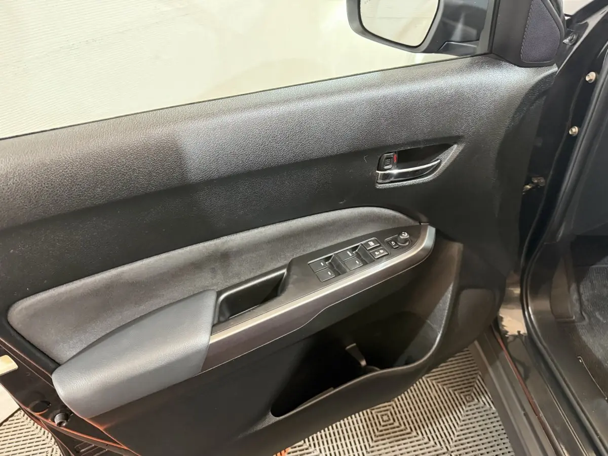 Vue rapprochée de la porte avant gauche noire du Suzuki Vitara 2022 avec commandes électriques et poignée chromée.