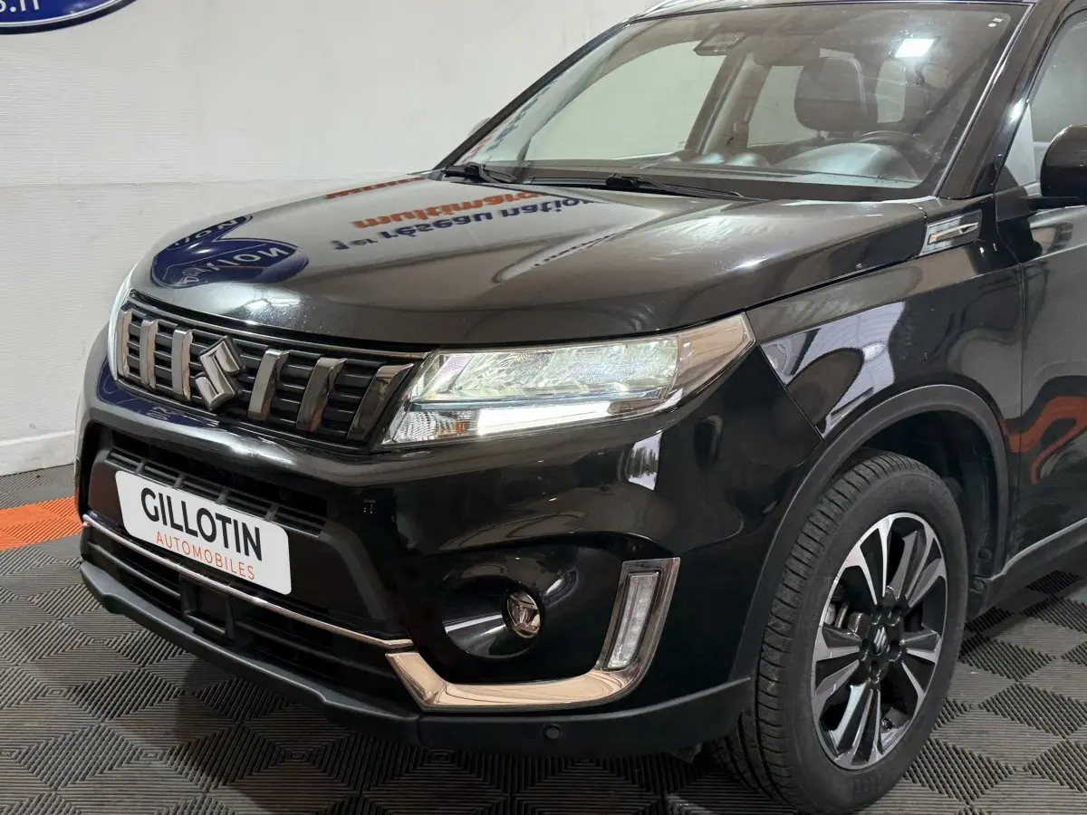 Vue 3/4 avant droite du Suzuki Vitara noir 2022 avec calandre distinctive et jantes alliage bicolores.