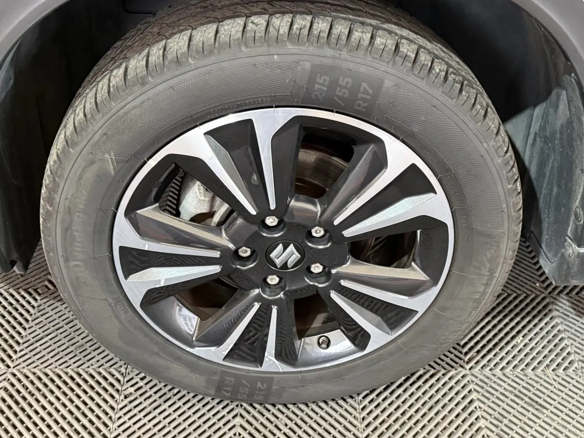 Gros plan sur la roue avant droite du Suzuki Vitara noir, mettant en valeur la jante alliage bicolore au design moderne.