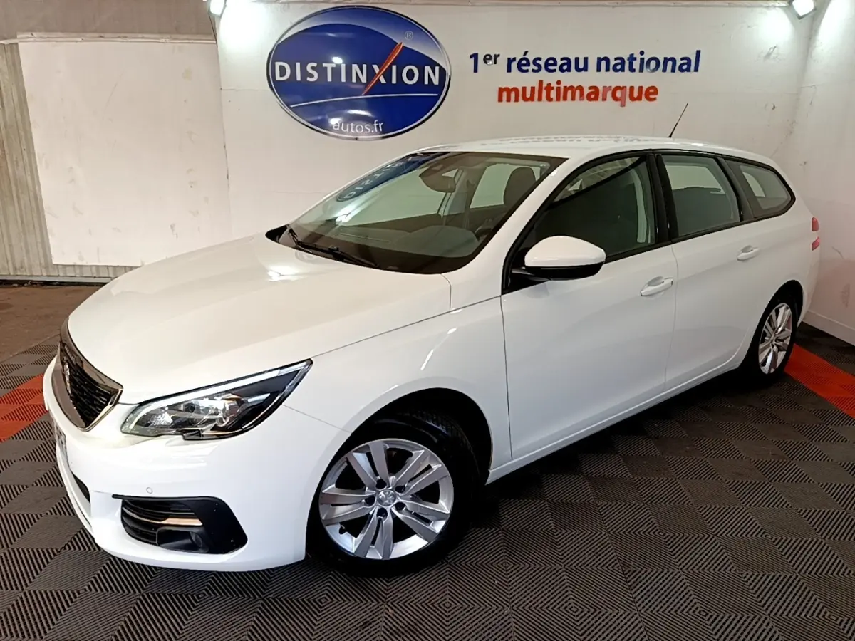 Peugeot 308 break blanc vue 3/4 avant droit dans un showroom avec logo Distinxion en arrière-plan.