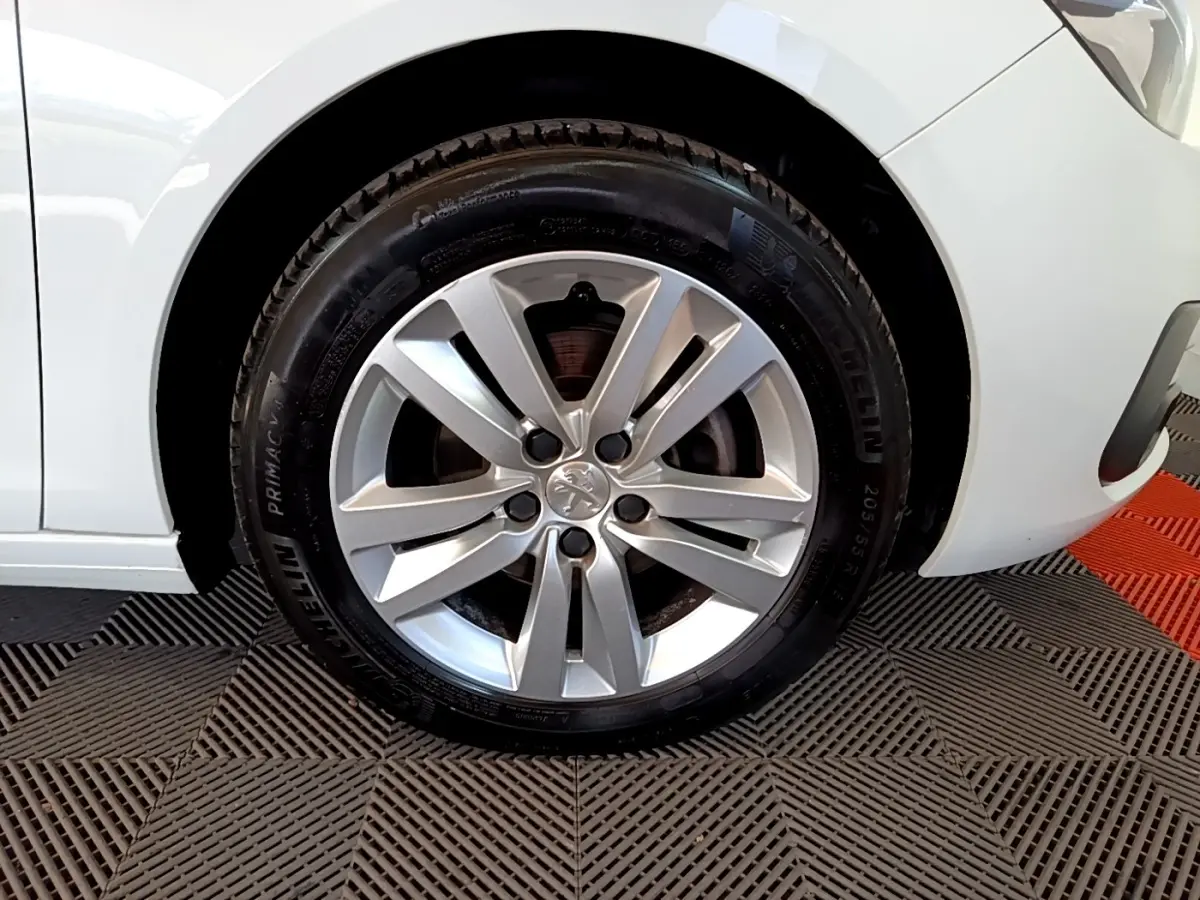 Gros plan sur la roue avant droite d’une Peugeot 308 blanche, jante alliage argentée et pneu Michelin visible.