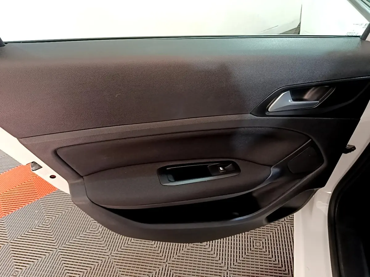 Vue intérieure de la porte avant droite blanche de la Peugeot 308 avec commande de vitre électrique et poignée argentée.