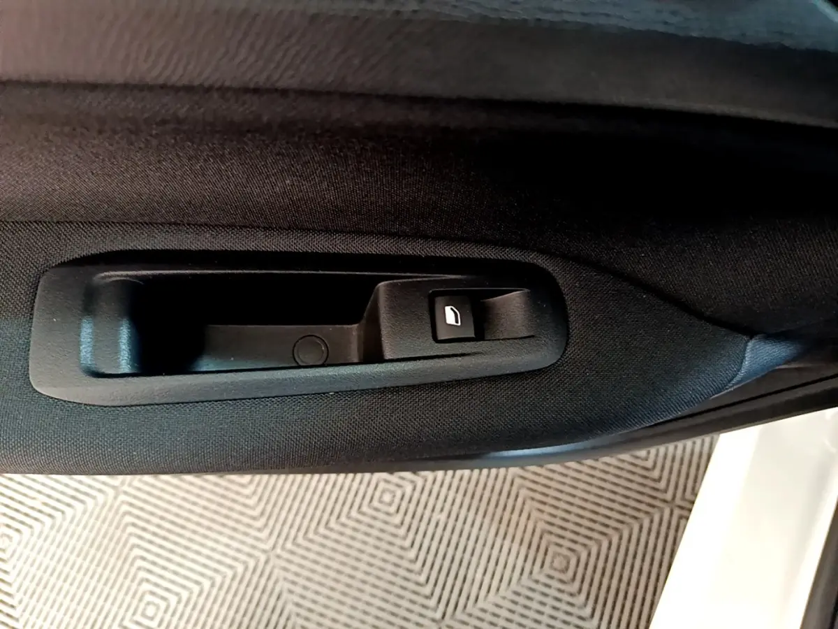 Poignée intérieure de porte arrière droite noire sur Peugeot 308 blanche, avec bouton de verrouillage.