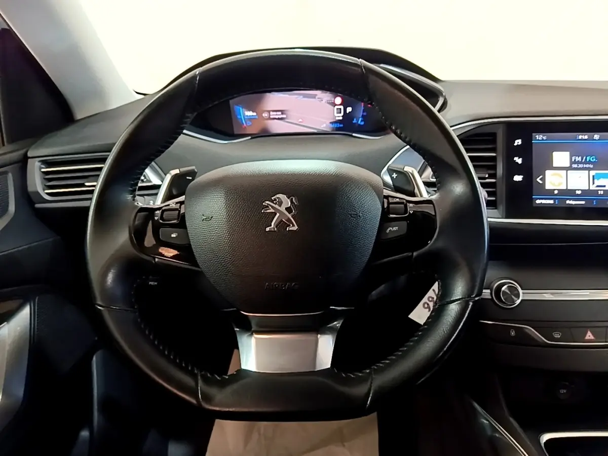 Vue centrée sur le volant cuir noir de la Peugeot 308 avec tableau de bord numérique et écran tactile latéral.