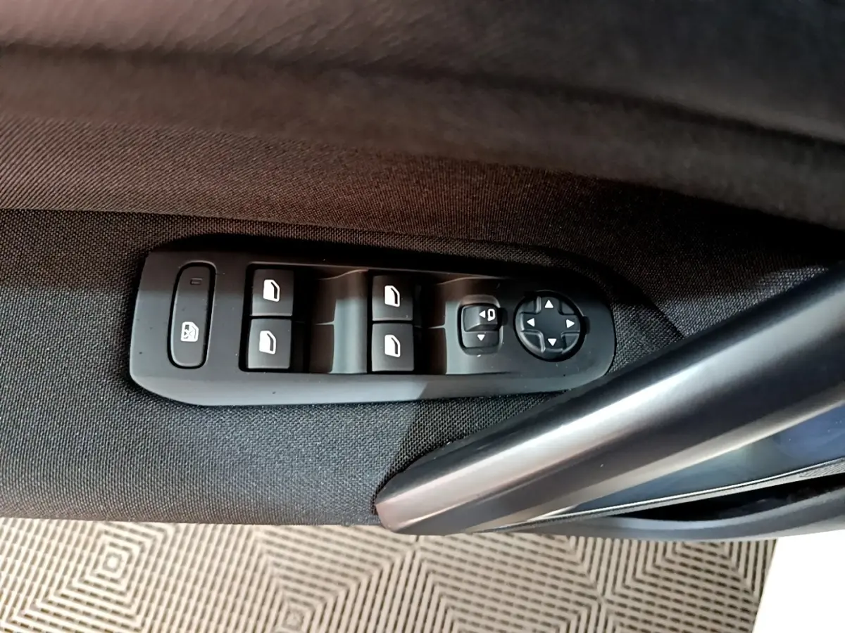 Détail des commandes des vitres et rétroviseurs sur la porte côté conducteur d’une Peugeot 308 blanche 2021.