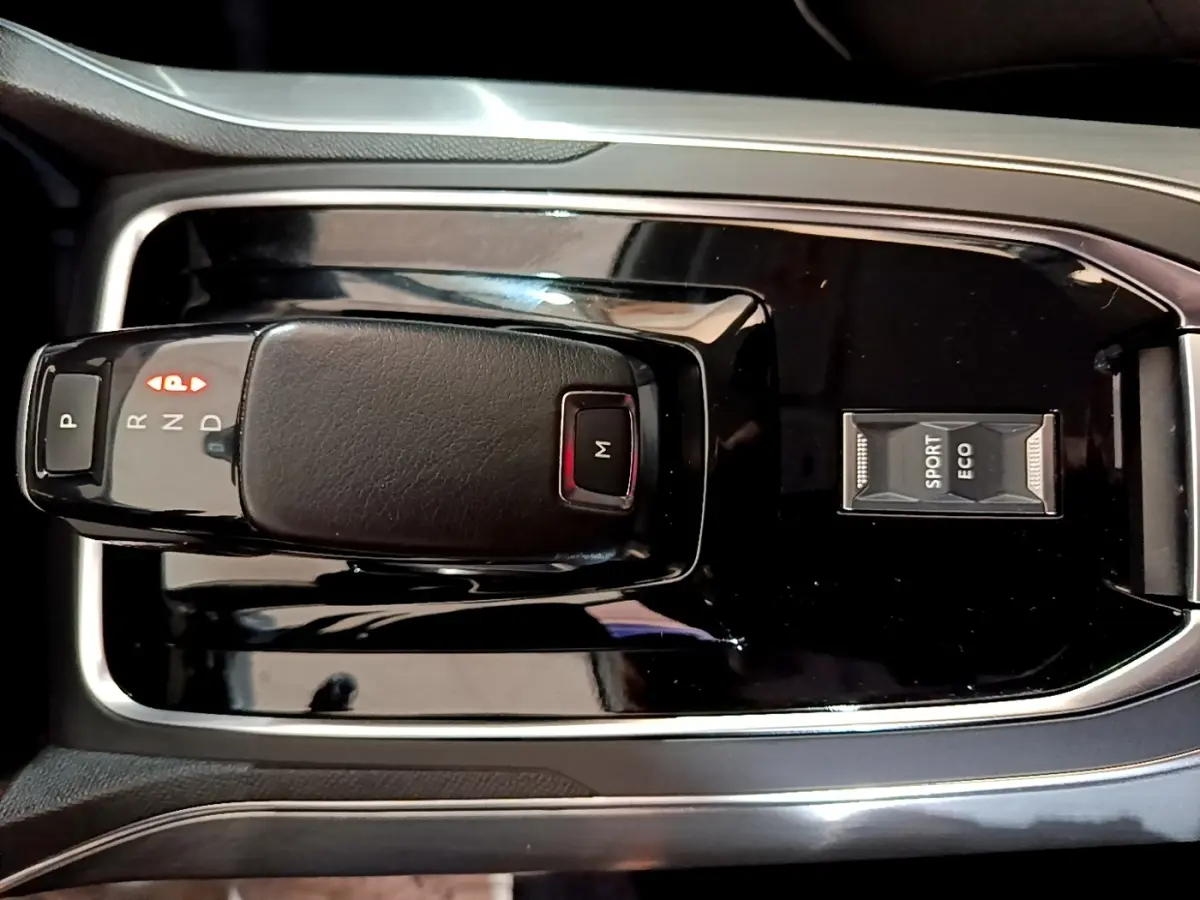 Gros plan sur la console centrale noire de la Peugeot 308 blanche, avec levier de vitesses automatique et sélecteur modes Sport/Eco.