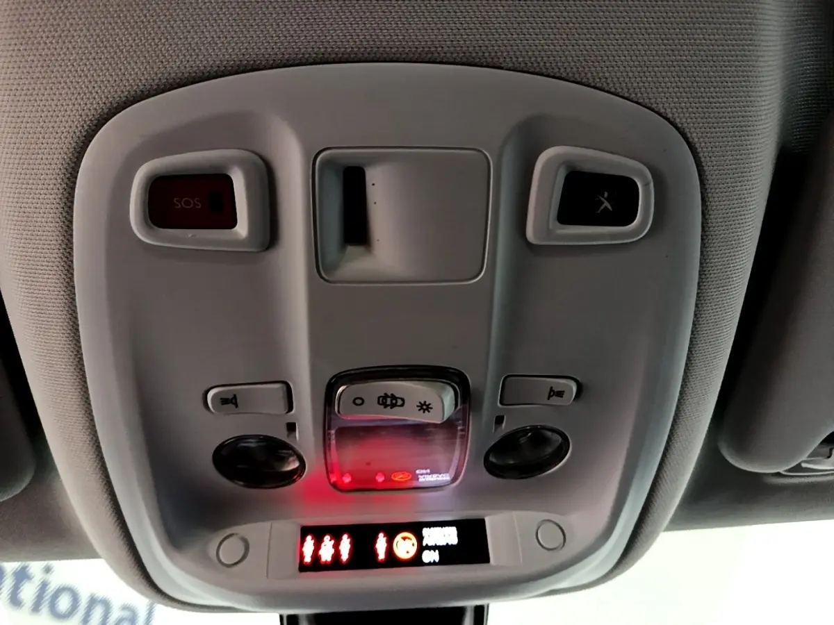 Vue intérieure du plafonnier avant de la Peugeot 308 blanche, avec commandes d’éclairage et bouton SOS éclairé en rouge.