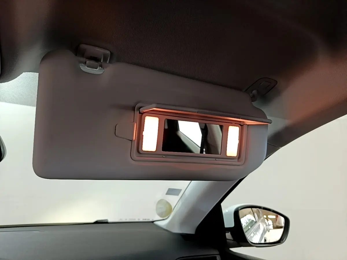 Détail du pare-soleil côté conducteur avec miroir éclairé dans l’habitacle d’une Peugeot 308 blanche.