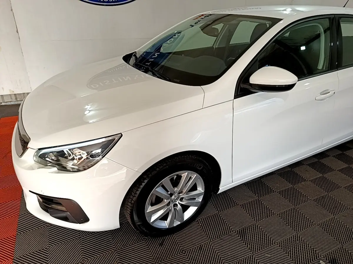 Vue 3/4 avant droit d'une Peugeot 308 blanche 2021 avec phares LED et jantes alliage argentées.