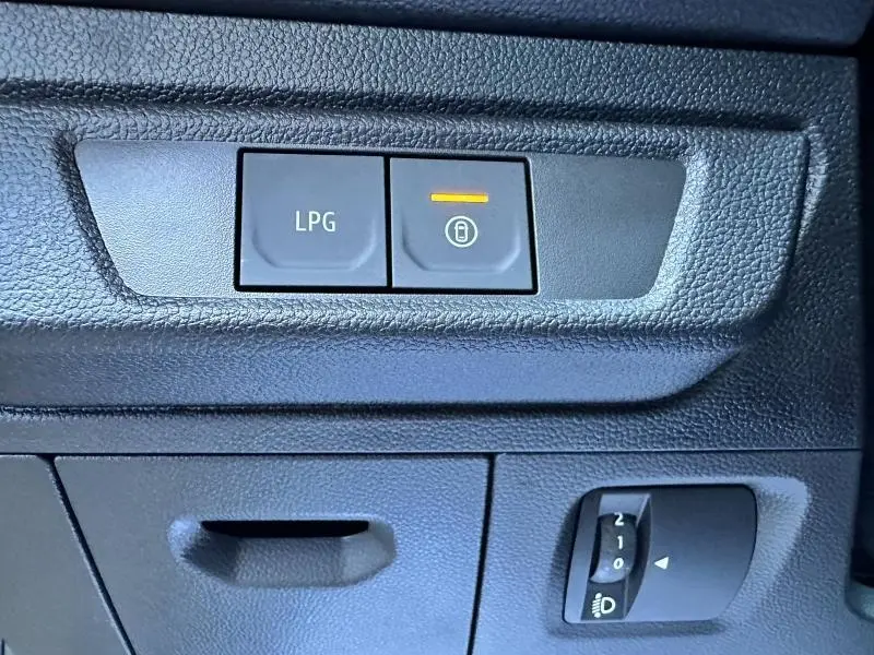 Gros plan sur les commandes LPG et verrouillage centralisé du tableau de bord noir de la Dacia Sandero beige Safari.