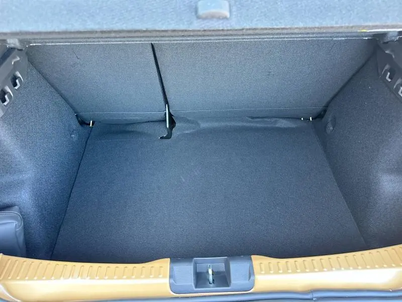 Vue plongeante sur le coffre spacieux et vide de la Dacia Sandero beige Safari, avec intérieur en tissu gris foncé.