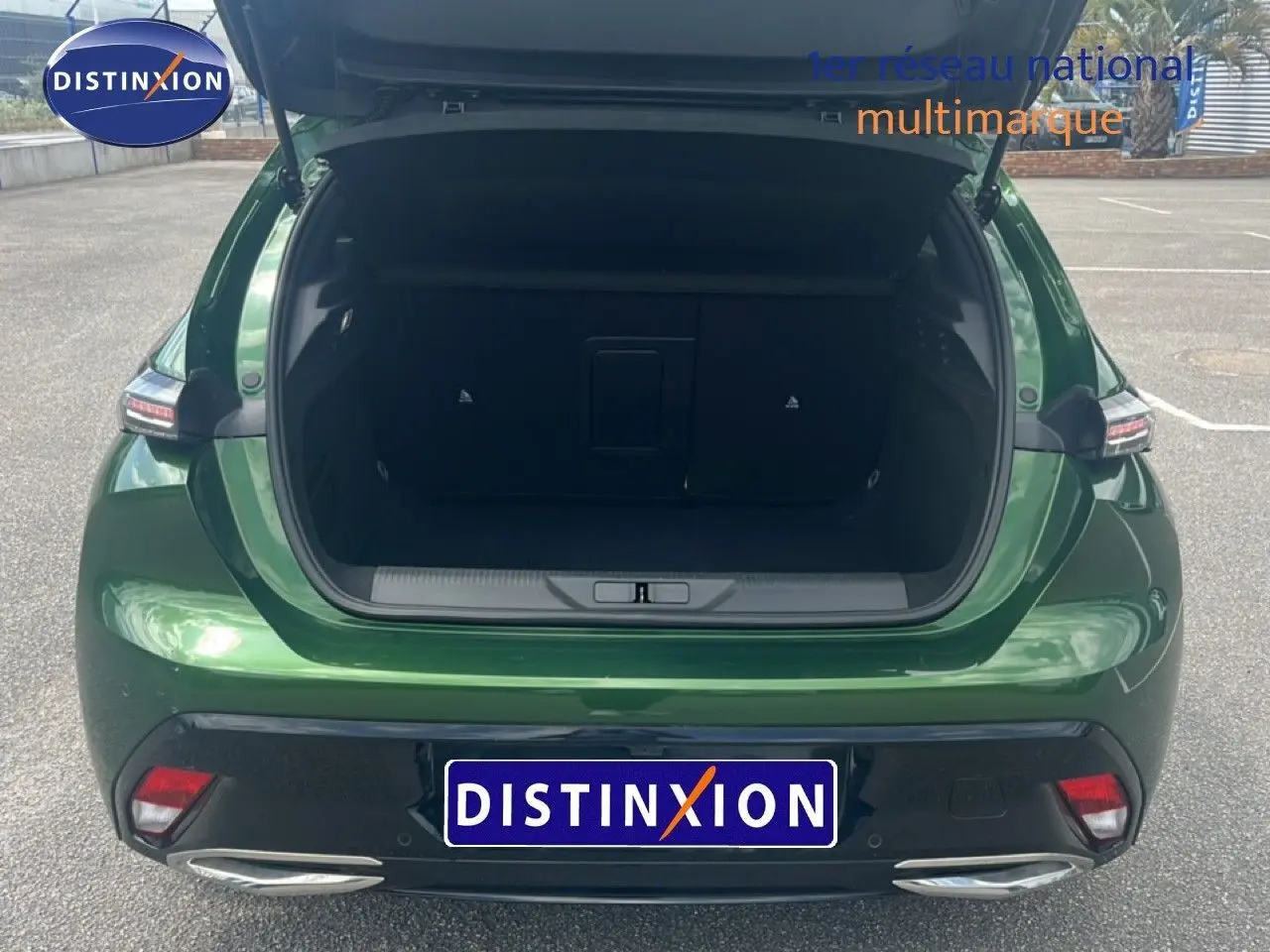 Vue arrière ouverte sur le coffre d'une Peugeot 308 2024 vert olivine métal, avec feux arrière et double sortie d'échappement visibles.