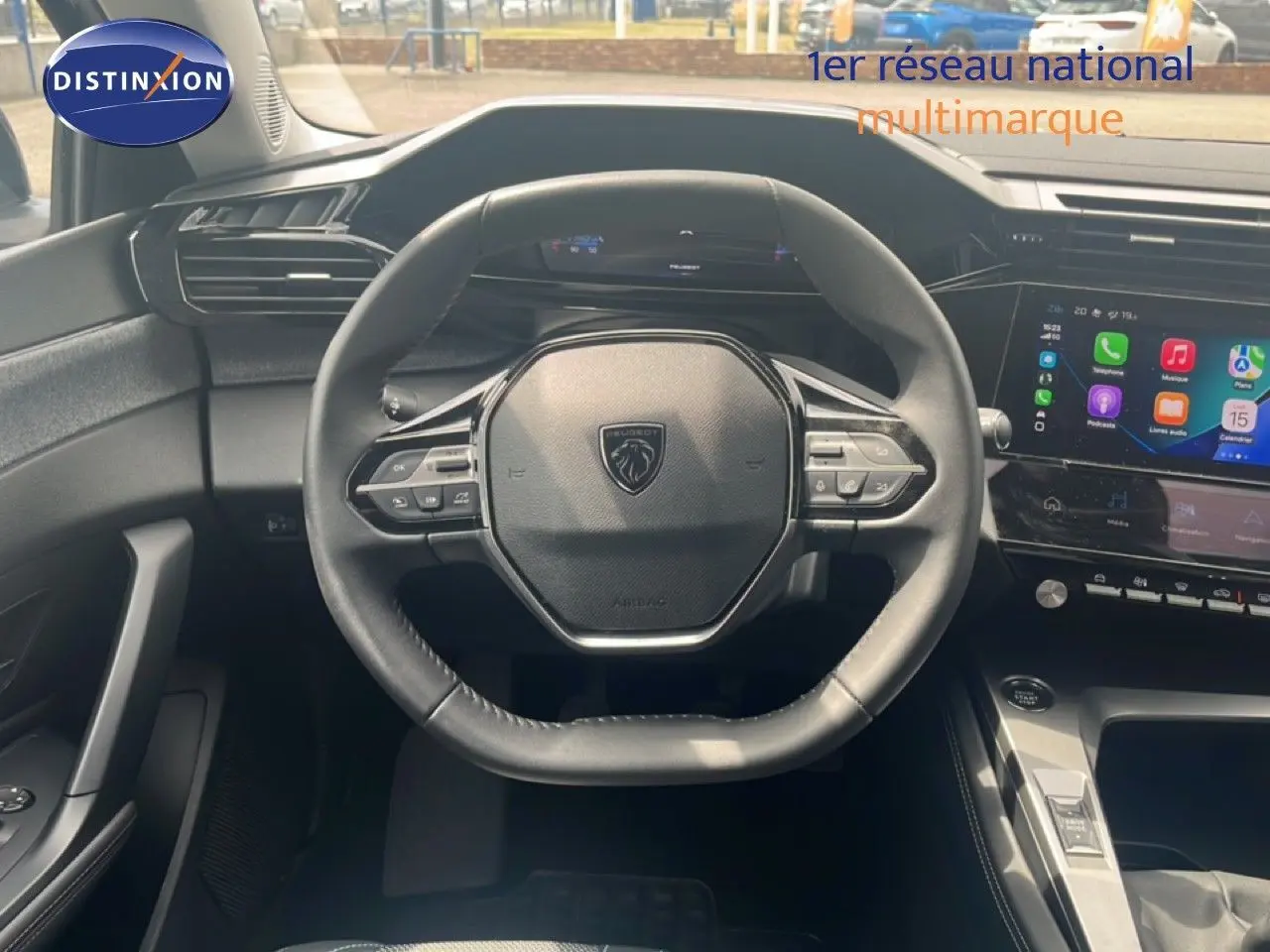 Vue intérieure centrée sur le volant cuir noir et l'écran tactile du tableau de bord de la Peugeot 308 2024.