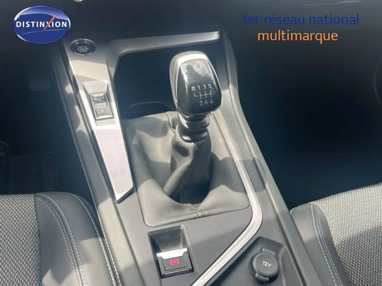 Gros plan sur le levier de vitesse manuel de la Peugeot 308 2024, intérieur gris avec coutures bleues, bouton Drive Mode visible.