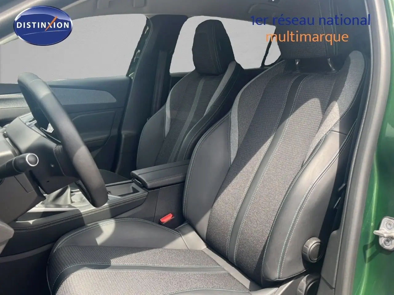Vue intérieure côté conducteur de la Peugeot 308 2024 vert olivine, sièges tissu et cuir gris noir avec volant multifonction.