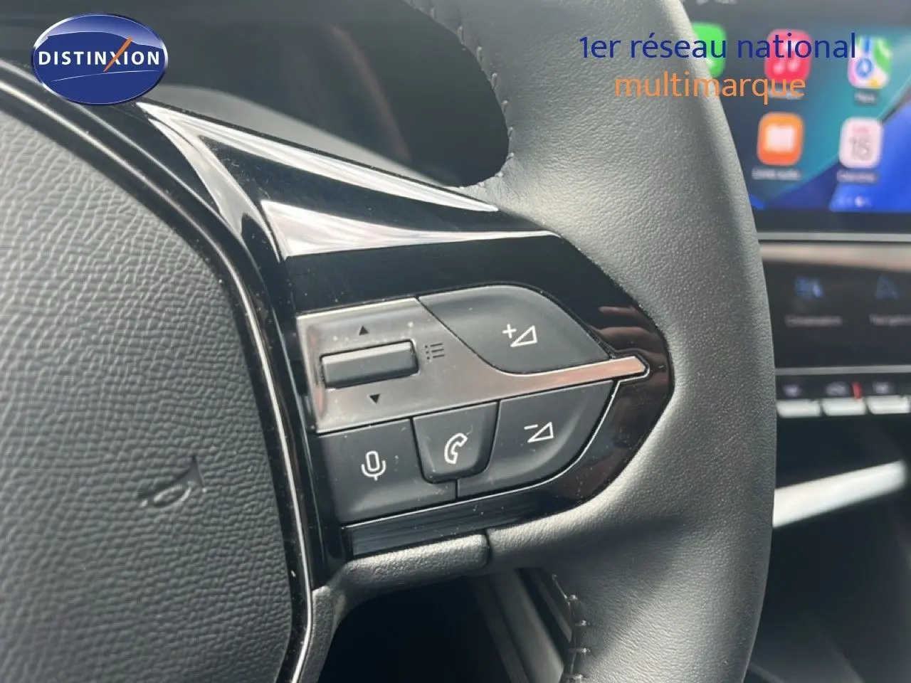 Gros plan sur les commandes au volant de la Peugeot 308 2024, finition Allure, avec cuir noir et écran tactile en arrière-plan.