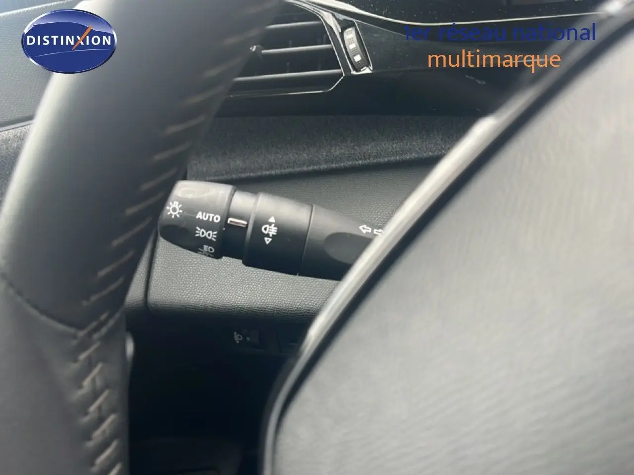 Gros plan sur la commande des feux et clignotants à gauche du volant d’une Peugeot 308 2024, intérieur gris noir.