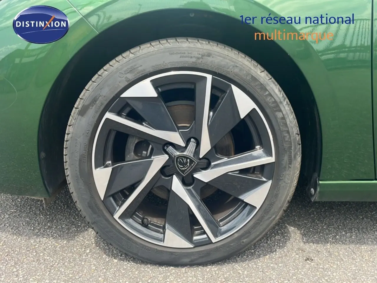 Gros plan sur la roue avant gauche d’une Peugeot 308 2024 vert olivine métal avec jante alliage noire et argent.