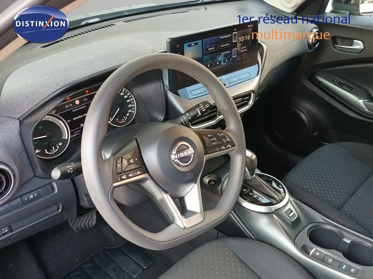 Vue intérieure centrée sur le volant et tableau de bord du Nissan Juke Hybrid 2025 avec finition tissu noir et écran tactile.