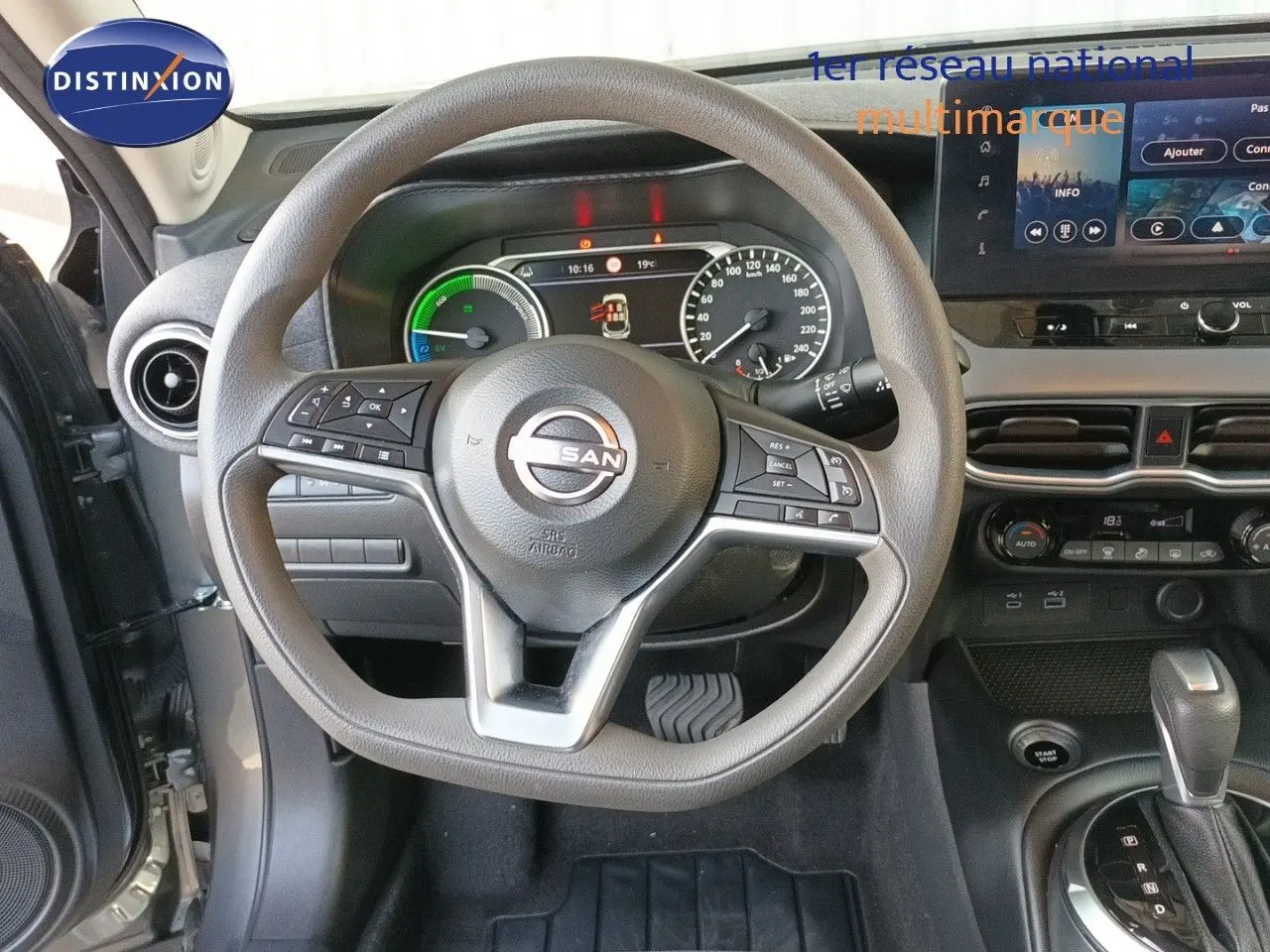 Vue intérieure centrée sur le volant et le tableau de bord du Nissan Juke Hybrid gris, avec écran tactile et commandes au volant.