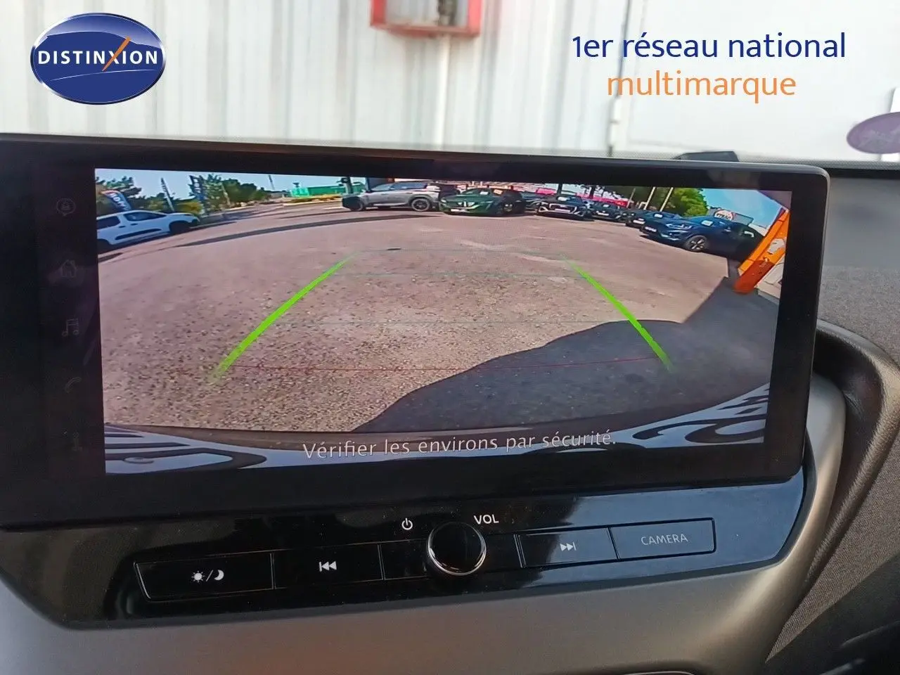 Écran intérieur montrant la caméra de recul du Nissan Juke Hybrid gris squale métal, avec lignes de guidage vertes.