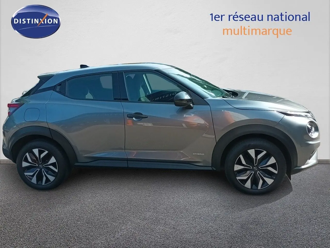 Vue de profil côté gauche d'un Nissan Juke hybride gris squale métal avec jantes distinctives et lignes modernes.