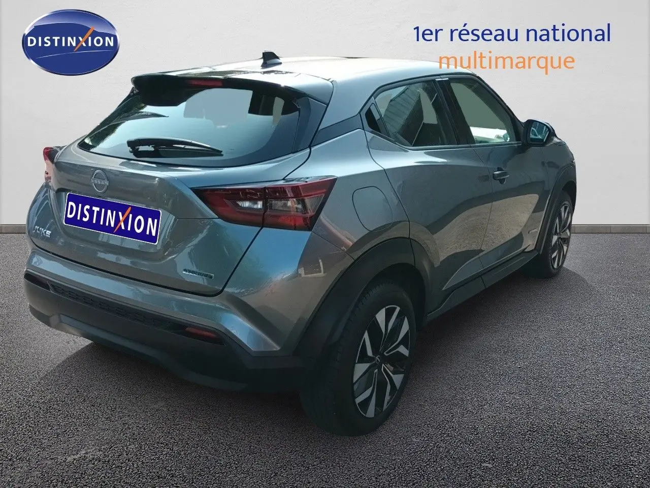 Vue 3/4 arrière droite du Nissan Juke Hybrid 2025 en gris squale métal avec jantes distinctives et feux arrière LED.